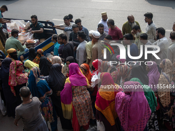 People wait in a long queue to buy government-subsidized food in Dhaka, Bangladesh, on December 10, 2024. (