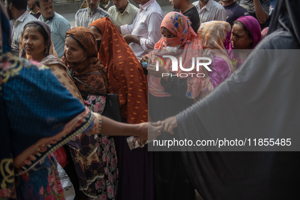 People wait in a long queue to buy government-subsidized food in Dhaka, Bangladesh, on December 10, 2024. 