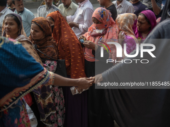 People wait in a long queue to buy government-subsidized food in Dhaka, Bangladesh, on December 10, 2024. (