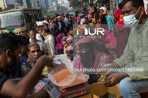 People wait in a long queue to buy government-subsidized food in Dhaka, Bangladesh, on December 10, 2024. 