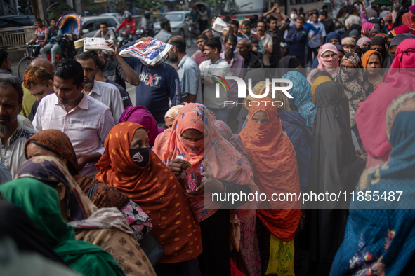 People wait in a long queue to buy government-subsidized food in Dhaka, Bangladesh, on December 10, 2024. 