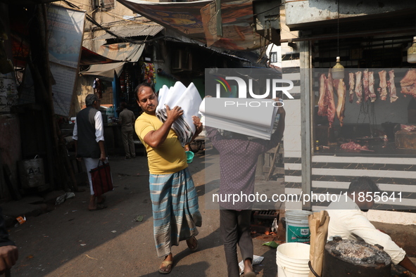 Workers carry English calendars ahead of New Year 2025, at a workshop in Kolkata, India, on December 11, 2024. 