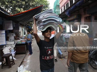 A worker carries English calendars ahead of New Year 2025 at a workshop in Kolkata, India, on December 11, 2024. (