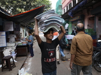 A worker carries English calendars ahead of New Year 2025 at a workshop in Kolkata, India, on December 11, 2024. (