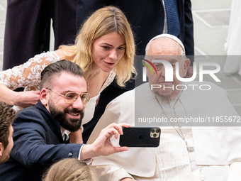 Pope Francis poses for a selfie with newlyweds at the end of the weekly general audience at Paul VI Hall in The Vatican, on December 11, 202...