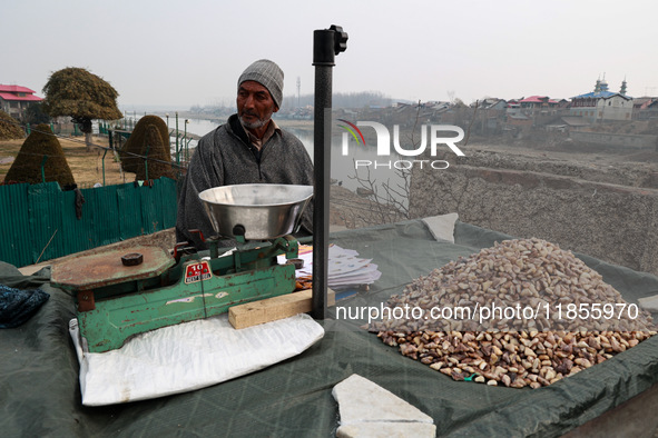 An elderly man sells shell-removed water chestnuts as he waits for customers near Jama Masjid in Sopore, Jammu and Kashmir, India, on Decemb...