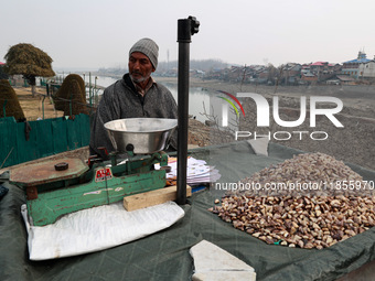 An elderly man sells shell-removed water chestnuts as he waits for customers near Jama Masjid in Sopore, Jammu and Kashmir, India, on Decemb...