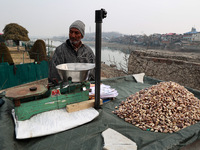 An elderly man sells shell-removed water chestnuts as he waits for customers near Jama Masjid in Sopore, Jammu and Kashmir, India, on Decemb...