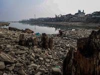 A woman washes utensils near a small water channel formed in the middle of the river Jhelum in Sopore, Jammu and Kashmir, India, on December...