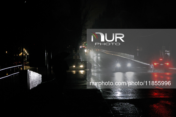 Cars move along a dark street in the Rusanivka neighborhood during a power cut in Kyiv, Ukraine, on December 7, 2024. 