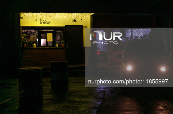 A car with headlights turned on is parked near a cafe operating during a power cut in the Rusanivka neighborhood in Kyiv, Ukraine, on Decemb...