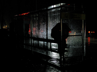 A person with an umbrella stands at a bus stop on Entuziastiv Street in the Rusanivka neighborhood during a power cut in Kyiv, Ukraine, on D...