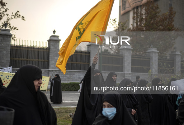 A veiled Iranian woman waves a flag of Lebanon's Hezbollah while participating in a rally to support the Hijab bill outside the Iranian Parl...