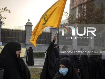 A veiled Iranian woman waves a flag of Lebanon's Hezbollah while participating in a rally to support the Hijab bill outside the Iranian Parl...