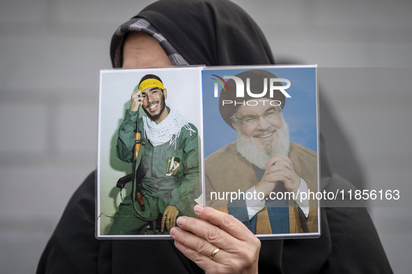 A veiled Iranian woman holds portraits of Lebanon's Hezbollah leader, Hassan Nasrallah, and an Iranian warrior while participating in a rall...