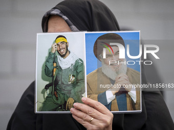 A veiled Iranian woman holds portraits of Lebanon's Hezbollah leader, Hassan Nasrallah, and an Iranian warrior while participating in a rall...