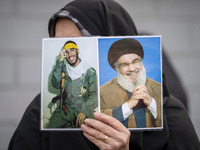 A veiled Iranian woman holds portraits of Lebanon's Hezbollah leader, Hassan Nasrallah, and an Iranian warrior while participating in a rall...