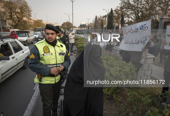 A veiled Iranian woman walks past a policeman monitoring an area outside the Iranian Parliament building during a rally to support the Hijab...