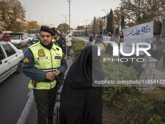 A veiled Iranian woman walks past a policeman monitoring an area outside the Iranian Parliament building during a rally to support the Hijab...