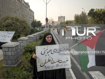 A veiled Iranian woman holds a Palestinian flag and a placard with Persian script that reads, ''Boycotting Zionist goods is a necessity to s...