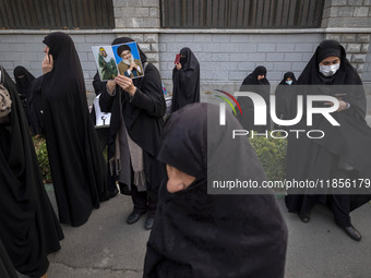 A veiled Iranian woman holds portraits of Lebanon's Hezbollah leader, Hassan Nasrallah, and an Iranian warrior while participating in a rall...