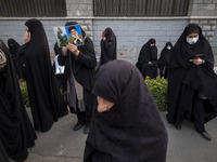 A veiled Iranian woman holds portraits of Lebanon's Hezbollah leader, Hassan Nasrallah, and an Iranian warrior while participating in a rall...