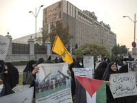 A small group of veiled Iranian women holds a flag of Lebanon's Hezbollah, a Palestinian flag, and placards while participating in a rally t...