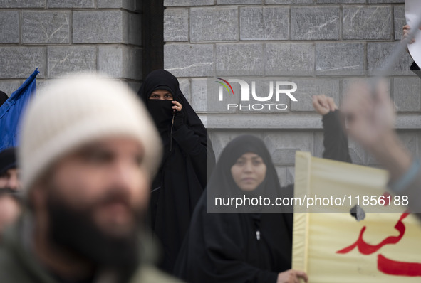 A veiled Iranian woman looks on as another veiled woman shouts slogans during a rally to support the Hijab bill outside the Iranian Parliame...