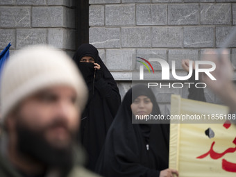 A veiled Iranian woman looks on as another veiled woman shouts slogans during a rally to support the Hijab bill outside the Iranian Parliame...