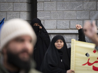 A veiled Iranian woman looks on as another veiled woman shouts slogans during a rally to support the Hijab bill outside the Iranian Parliame...