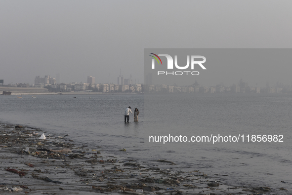 A boy takes a mobile photo of a girl near a sea beach in Mumbai, India, on December 11, 2024. 