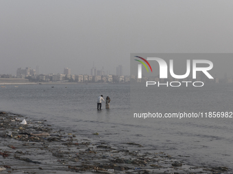 A boy takes a mobile photo of a girl near a sea beach in Mumbai, India, on December 11, 2024. (