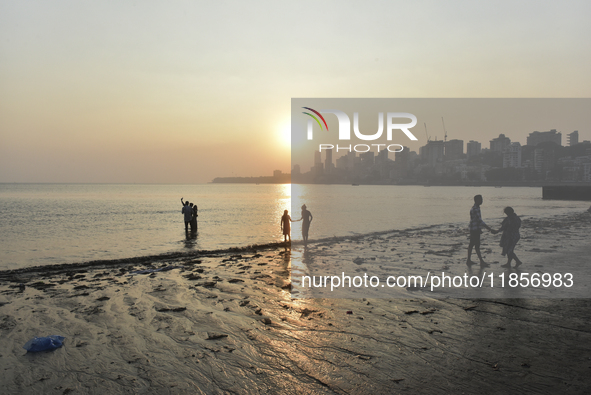 People spend time during the evening near a sea beach in Mumbai, India, on December 11, 2024. 