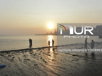 People spend time during the evening near a sea beach in Mumbai, India, on December 11, 2024. (