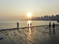 People spend time during the evening near a sea beach in Mumbai, India, on December 11, 2024. (