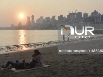 Couples are seen at a sea beach with a backdrop of a cityscape in Mumbai, India, on December 11, 2024. (