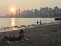 Couples are seen at a sea beach with a backdrop of a cityscape in Mumbai, India, on December 11, 2024. (