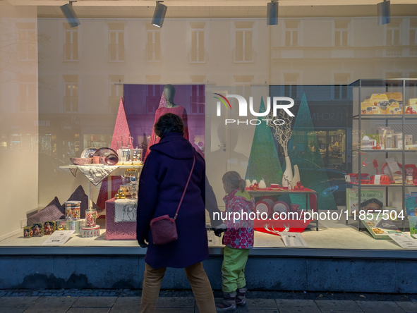 A mother and her child walk in front of festive Christmas displays in Munich, Bavaria, Germany, on December 11, 2024. They stroll in front o...