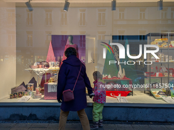 A mother and her child walk in front of festive Christmas displays in Munich, Bavaria, Germany, on December 11, 2024. They stroll in front o...