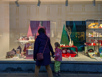 A mother and her child walk in front of festive Christmas displays in Munich, Bavaria, Germany, on December 11, 2024. They stroll in front o...