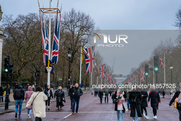 People walk along The Mall under festive Union Jack flags, in London, United Kingdom, on December 7, 2024. 