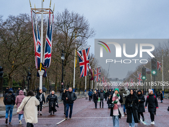 People walk along The Mall under festive Union Jack flags, in London, United Kingdom, on December 7, 2024. (