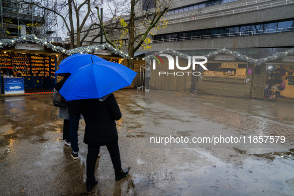 People with umbrellas walk through a near-empty Christmas market during Storm Darragh on December 7, 2024, in London, United Kingdom. London...