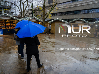 People with umbrellas walk through a near-empty Christmas market during Storm Darragh on December 7, 2024, in London, United Kingdom. London...