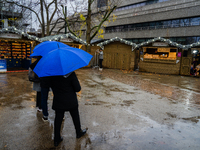 People with umbrellas walk through a near-empty Christmas market during Storm Darragh on December 7, 2024, in London, United Kingdom. London...