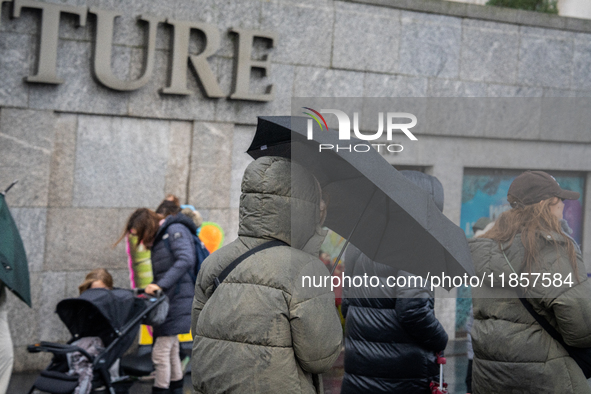 People dressed in winter coats carry umbrellas as they navigate rainy weather during Storm Darragh on December 7, 2024, in London, United Ki...