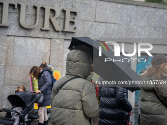 People dressed in winter coats carry umbrellas as they navigate rainy weather during Storm Darragh on December 7, 2024, in London, United Ki...