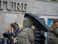 People dressed in winter coats carry umbrellas as they navigate rainy weather during Storm Darragh on December 7, 2024, in London, United Ki...