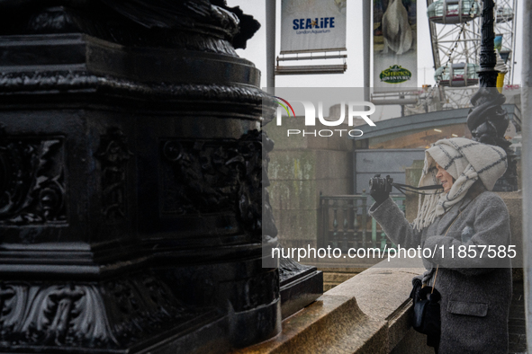 A woman with scarf and coat photographs a scene near the London Eye during Storm Darragh on December 7, 2024, in London, United Kingdom. Lon...