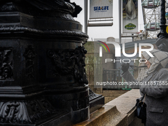 A woman with scarf and coat photographs a scene near the London Eye during Storm Darragh on December 7, 2024, in London, United Kingdom. Lon...